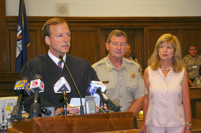 Judge Scott Crichton addresses audience in Courtroom G, while Sheriff Steve Prator and wife Carolyn Prator watch.